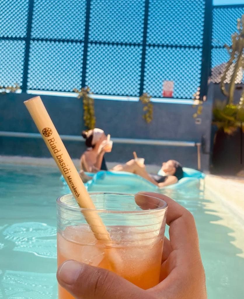 Cocktail tenu au-dessus d'une piscine, paille gravée